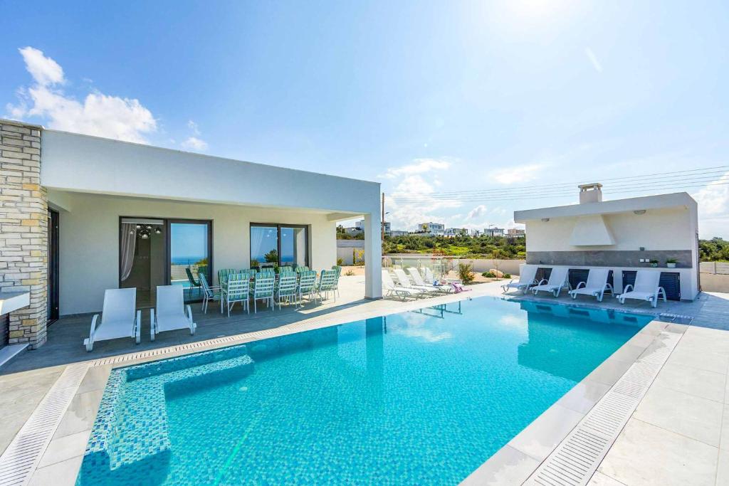 - une piscine avec des chaises et une maison dans l'établissement Villa Pleiades, à Peyia