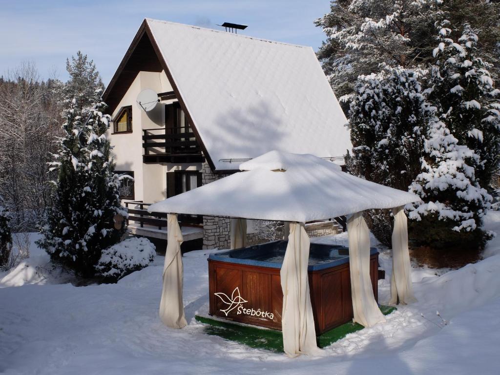 una bañera de hidromasaje frente a una casa en la nieve en Chata Štebôtka s jacuzzi en Nálepkovo