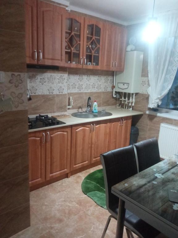 a kitchen with wooden cabinets and a dining table at Apartament Bia in Lupeni