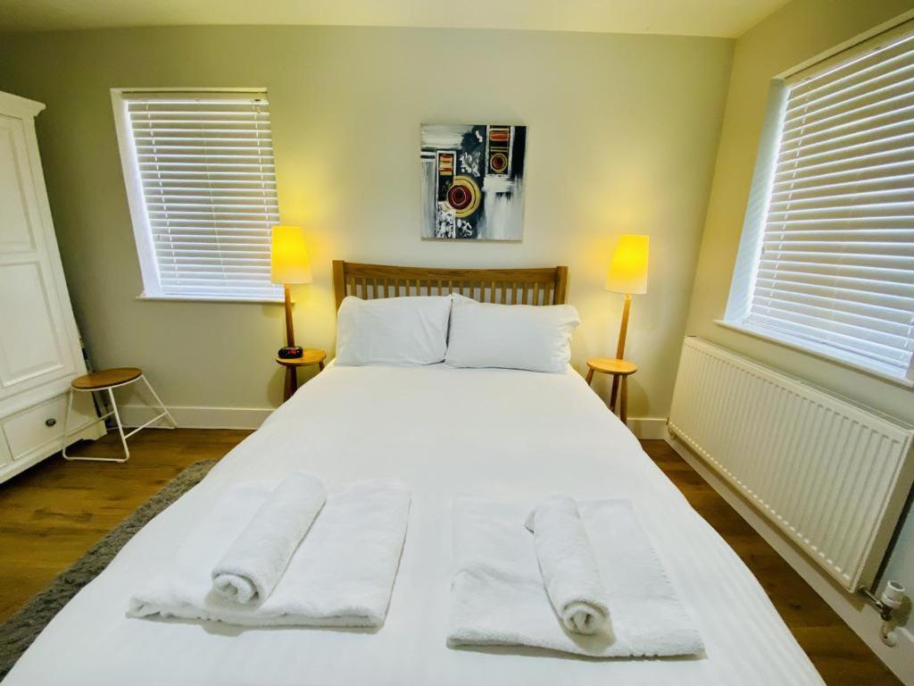 a bedroom with a large white bed with towels on it at Cloud9StayZ at The Oakridge in Woking