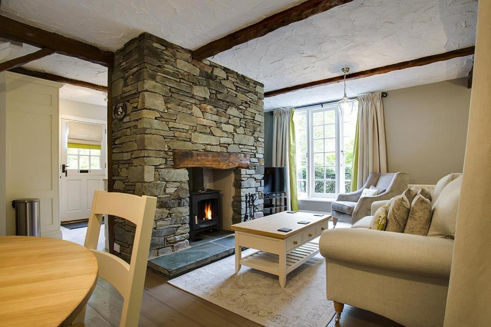 a living room with a stone fireplace and a couch at Acorn Cottage in Grasmere