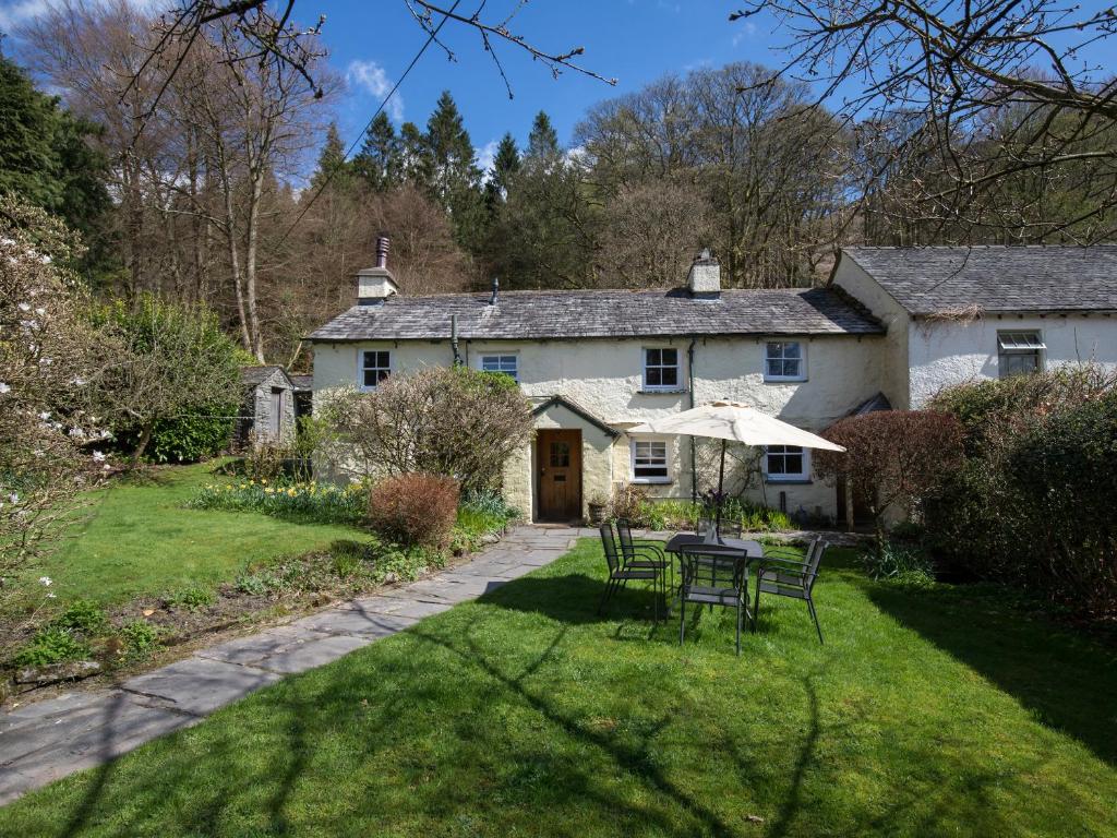 a house with a table and chairs in the yard at Fir Tree Cottage in Ambleside