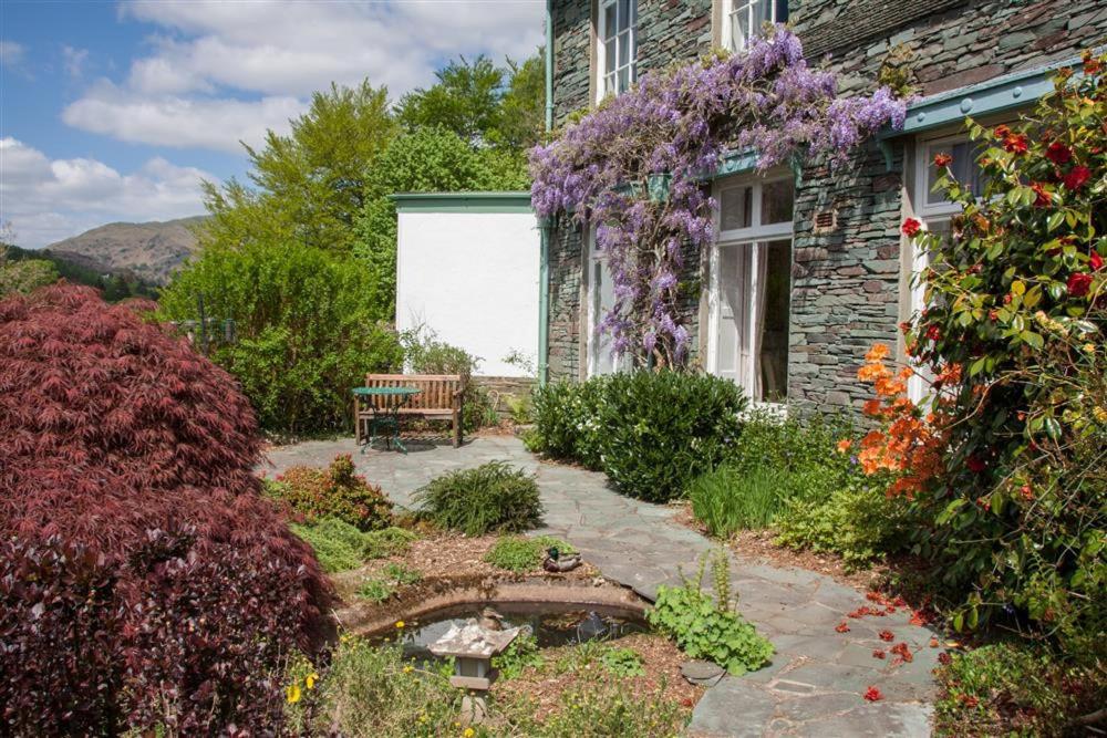 un jardín con un banco y flores frente a una casa en Betamere, en Ambleside