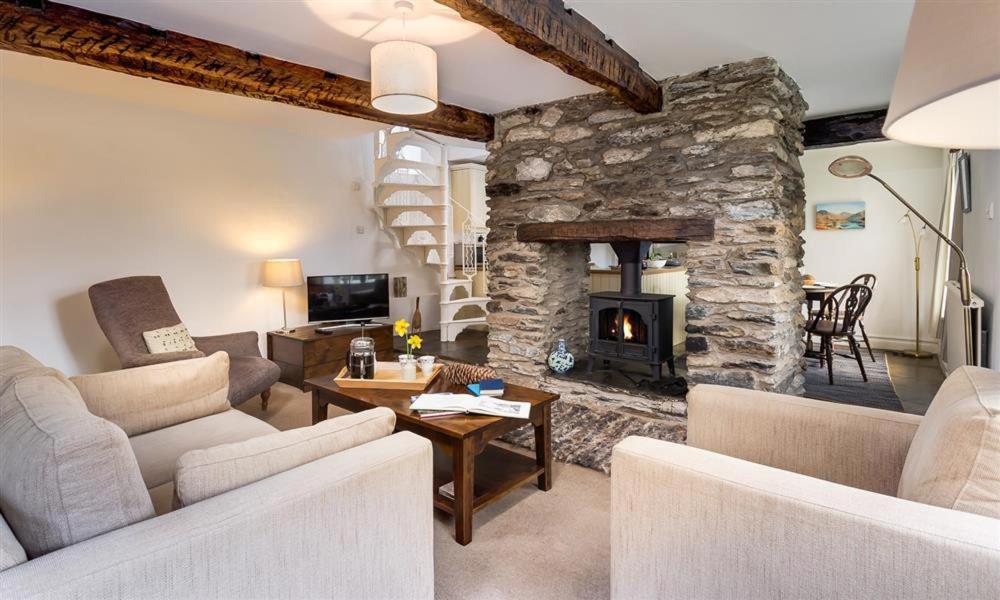 a living room with a stone fireplace and couches at Camellia Cottage in Crook