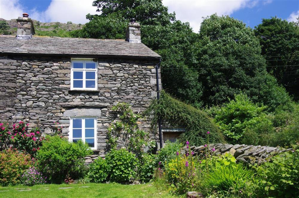 an old stone house with flowers in front of it at Thomas Cottage in Penrith