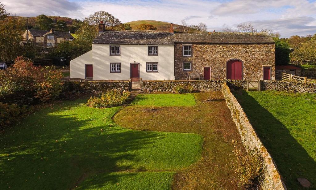 an old stone house with red doors and a yard at Low Longthwaite Farm in Watermillock