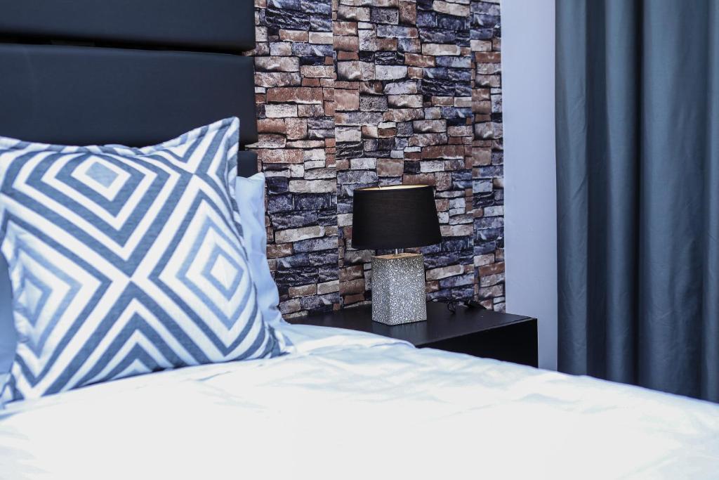 a bedroom with a bed and a brick wall at Delux Guesthouse in Volksrust