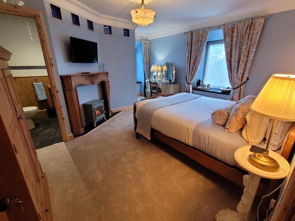 um quarto com uma cama com um candeeiro e uma lareira em Hideaway Escapes, Farmhouse B&B & Holiday Home, Ideal family stay or Romantic break, Friendly animals on our smallholding in beautiful Pembrokeshire setting close to Narberth em Narberth