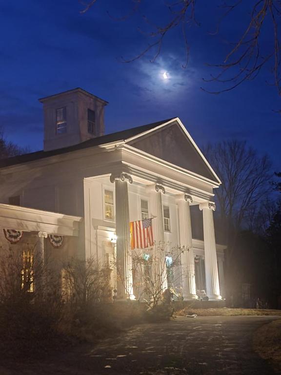 a white house with a flag on the side of it at House of 1833 Bed and Breakfast in Mystic