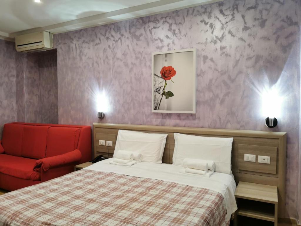 a bedroom with a bed and a red chair at Hotel Orchidea in Turin