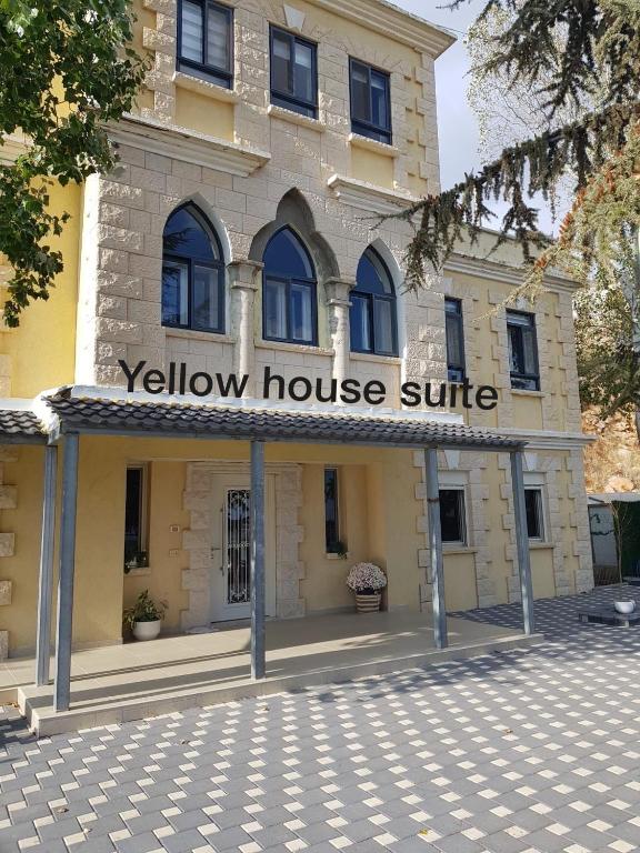 ein gelbes Haus mit einem Schild auf der Vorderseite in der Unterkunft Yellow House Suite in Madschdal Schams