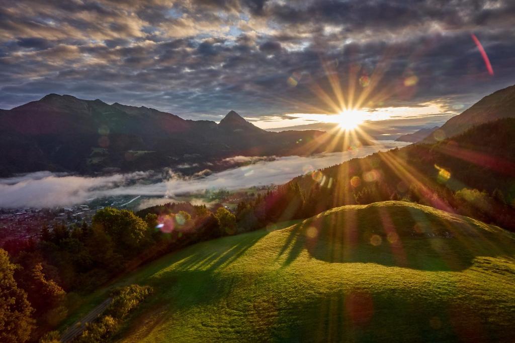 una vista del sol saliendo sobre un campo con el sol brillando en Gasthof Lamprechtbauer, en Kötschach-Mauthen