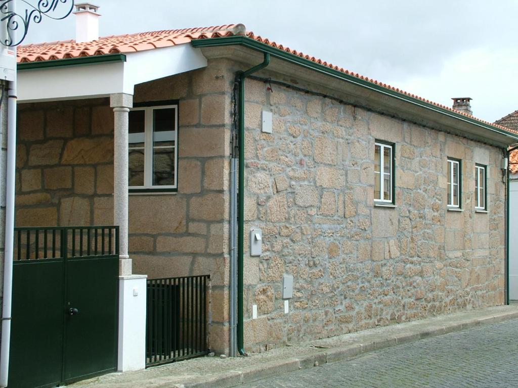 una casa de ladrillo con una puerta verde en una calle en Casa d Toninha - Casas de Campo - Turismo Espaço Rural - AL en Sernancelhe