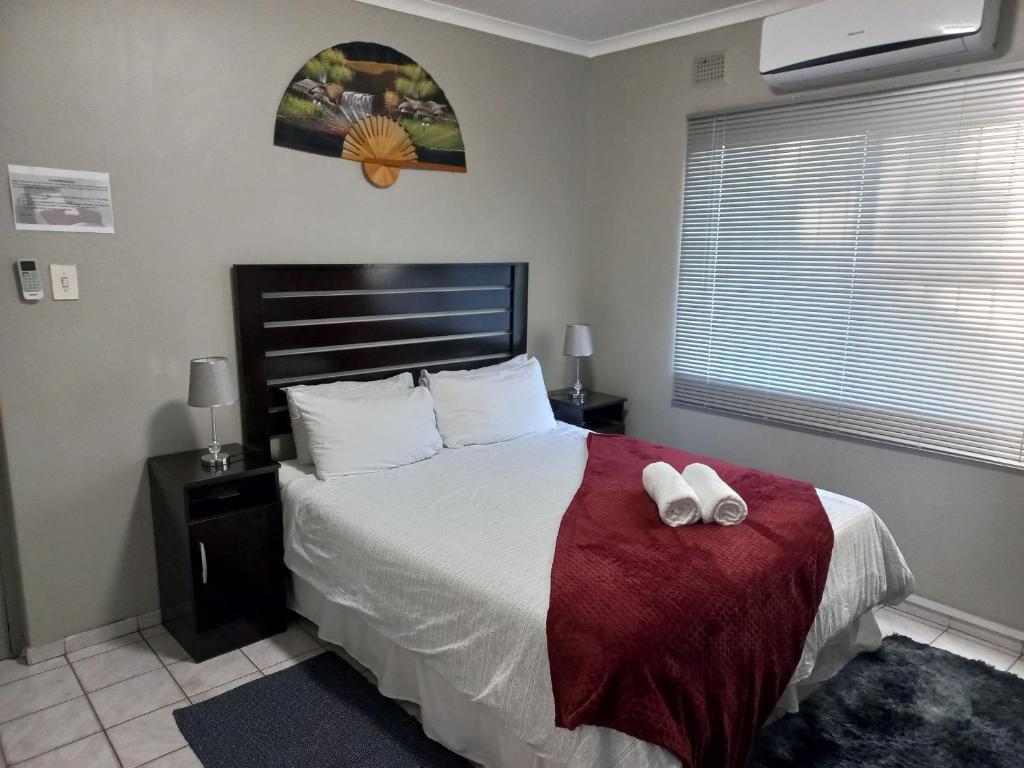 a bedroom with a bed with two white towels on it at Elegant 1-Bedroom Apartment with pool. in Richards Bay