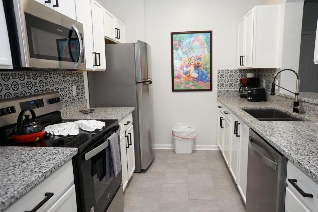 cocina con armarios blancos y nevera de acero inoxidable en Windsor Hills Resort- 302, en Orlando