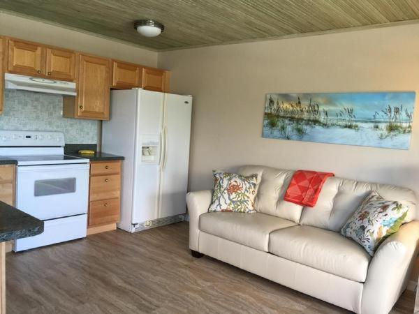 uma sala de estar com um sofá e um frigorífico branco em Richard Arms Unit 12 em Cocoa Beach