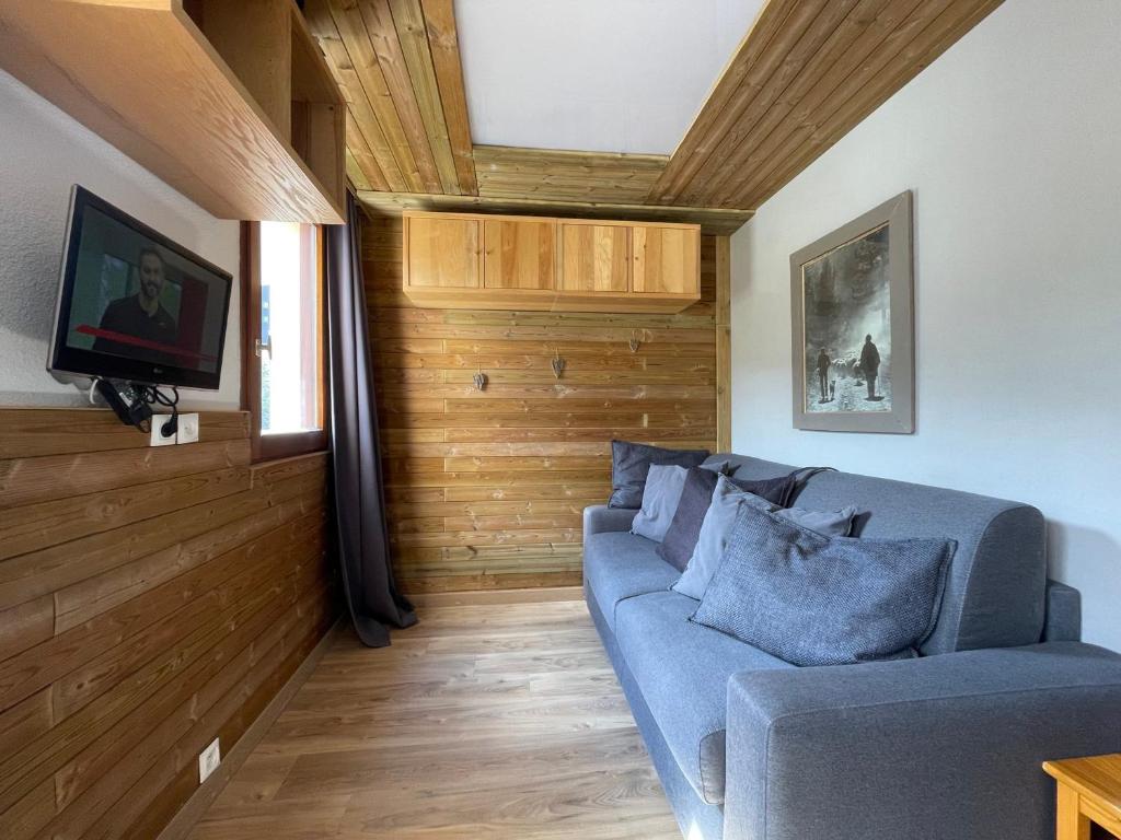 sala de estar con sofá azul y paredes de madera en Studio Les Menuires, 1 pièce, 3 personnes - FR-1-452-91 en Les Menuires