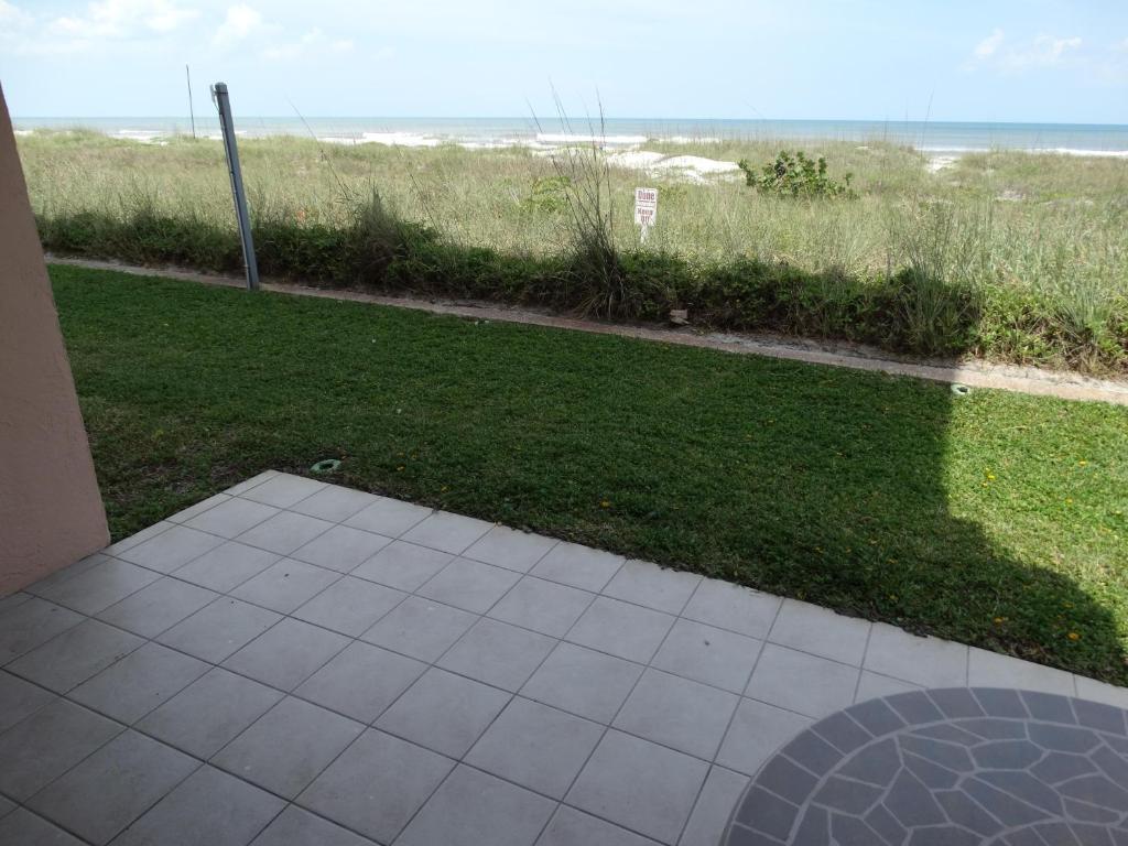 a patio with a view of a lawn and the beach at Spanish Main Unit 4- Direct Oceanfront Condo! in Cocoa Beach