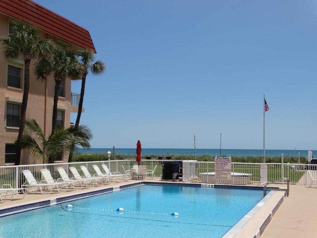 una piscina con sedie e l'oceano sullo sfondo di Spanish Main Unit 4- Direct Oceanfront Condo! a Cocoa Beach