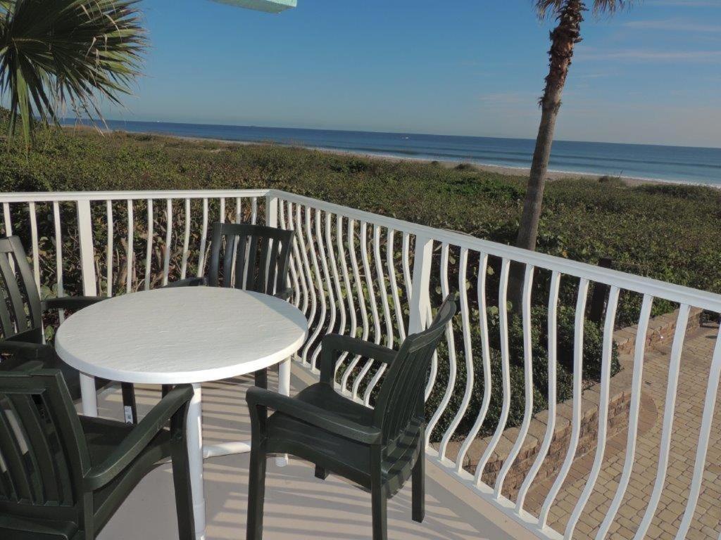 a table and chairs on a deck with the beach at Renovated, Ocean Beach Villas Unit 201- Direct Oceanfront Condo! in Cocoa Beach