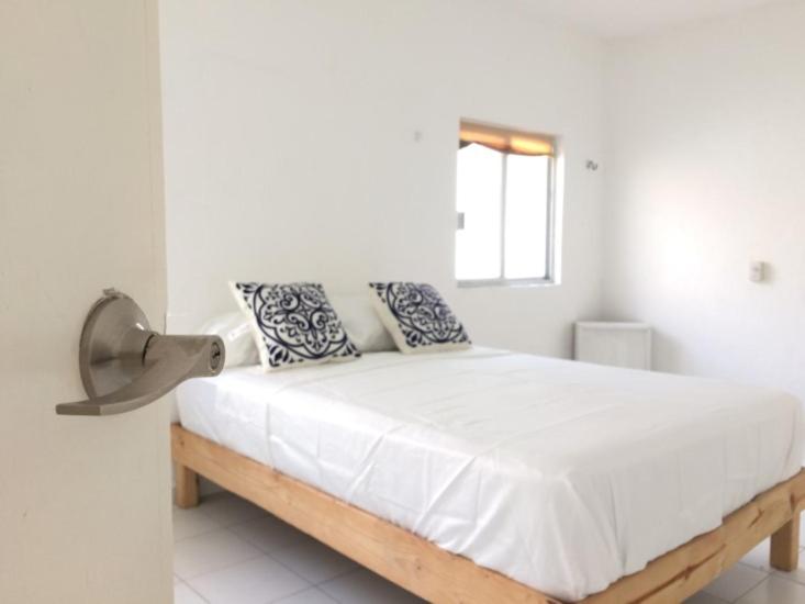 una camera da letto bianca con un grande letto bianco con cuscini blu di Apartment with fast WIFI near Cancun downtown a Cancún