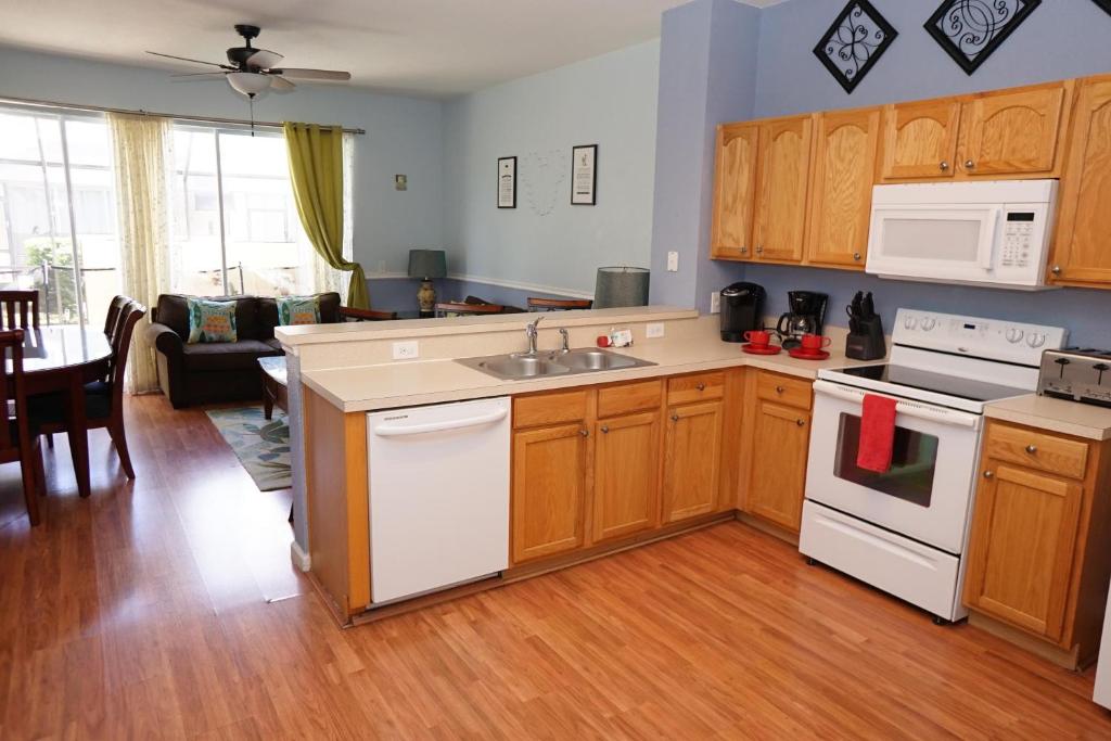 - une cuisine avec des placards en bois et des appareils blancs dans l'établissement Windsor Hills Resort- 7665 Sir Kaufmann, à Kissimmee