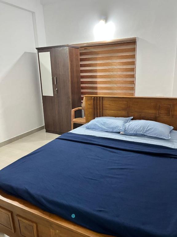 a bedroom with a large bed with a wooden headboard at Wayanad Biriyomz Residency, Kalpatta, Low Cost Rooms and Deluxe Apartment in Kalpetta