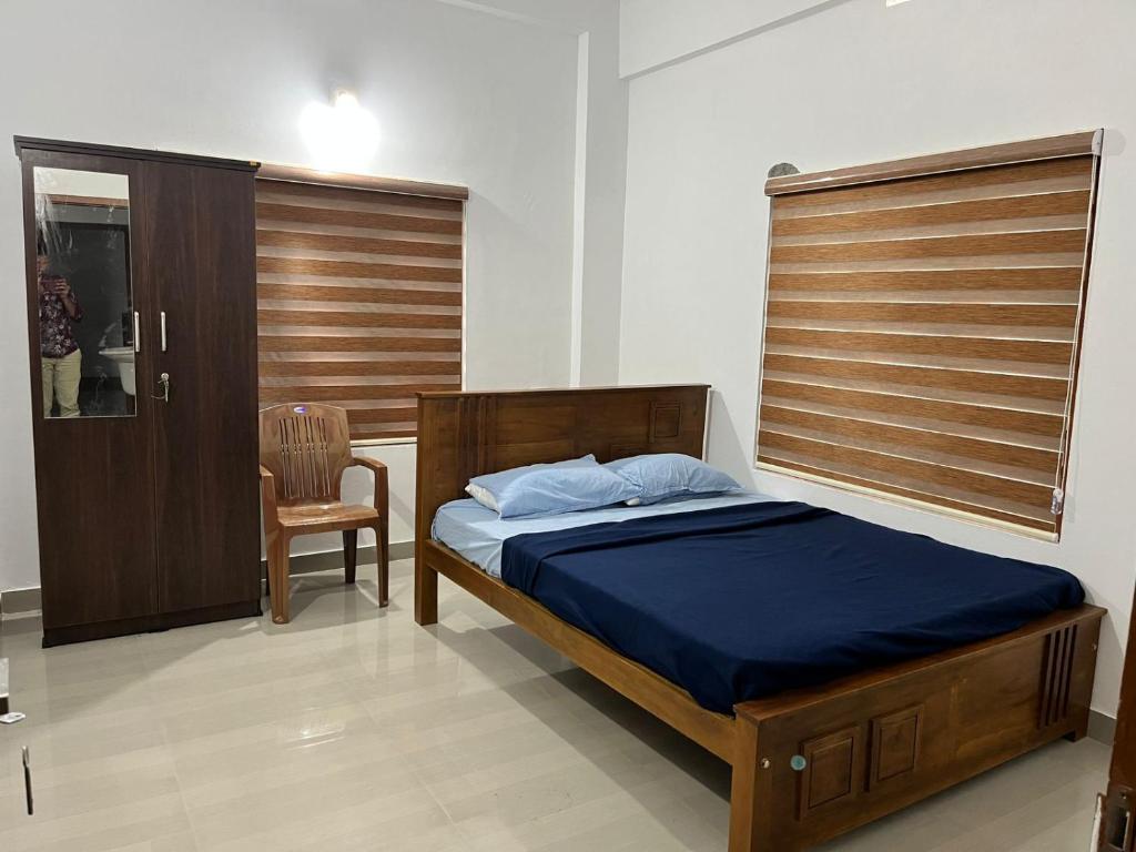 a bedroom with a bed and a chair and a window at Wayanad Biriyomz Residency, Kalpatta, Low Cost Rooms and Deluxe Apartment in Kalpetta