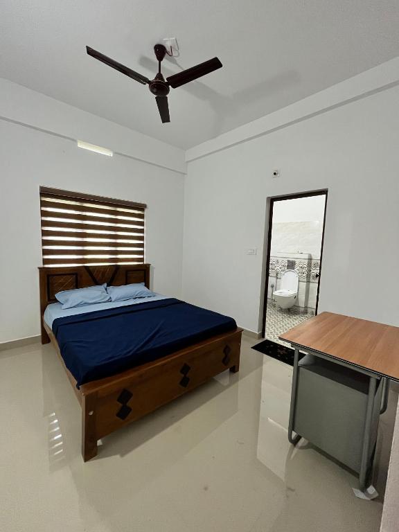 a bedroom with a bed and a ceiling fan at Wayanad Biriyomz Residency, Kalpatta, Low Cost Rooms and Deluxe Apartment in Kalpetta
