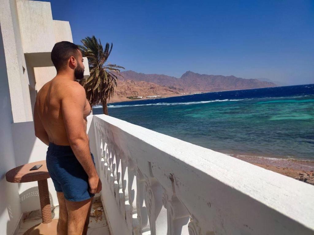 un homme debout sur un balcon donnant sur l'océan dans l'établissement Zarnouk beach house, à Dahab