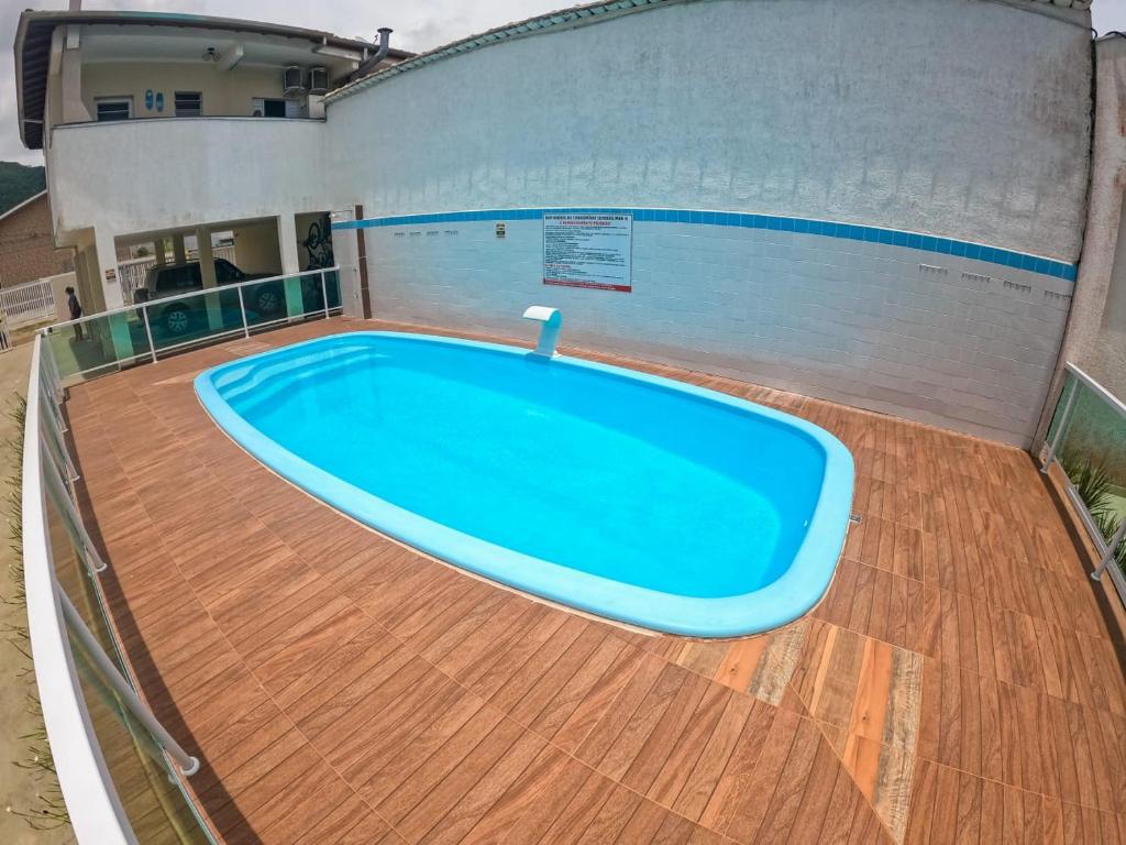 a large blue pool on a wooden floor in a building at APARTAMENTO COM PISCINA E CHURRASQUEIRA in Ubatuba