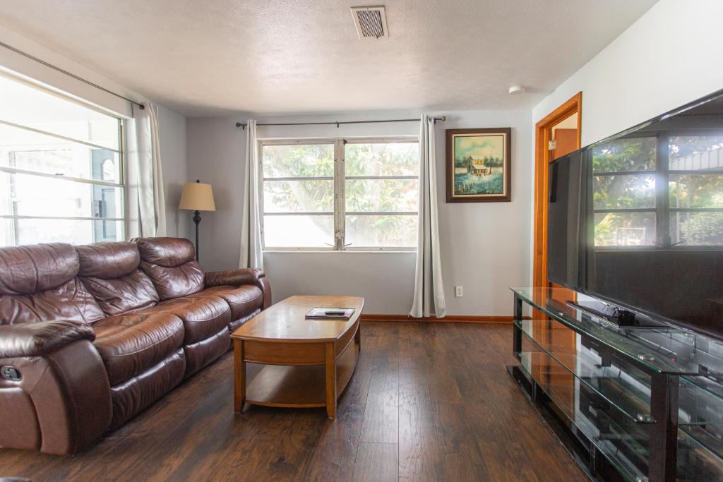a living room with a leather couch and a flat screen tv at Two Bedroom Home - Walking Distance from The Beach in Jacksonville Beach