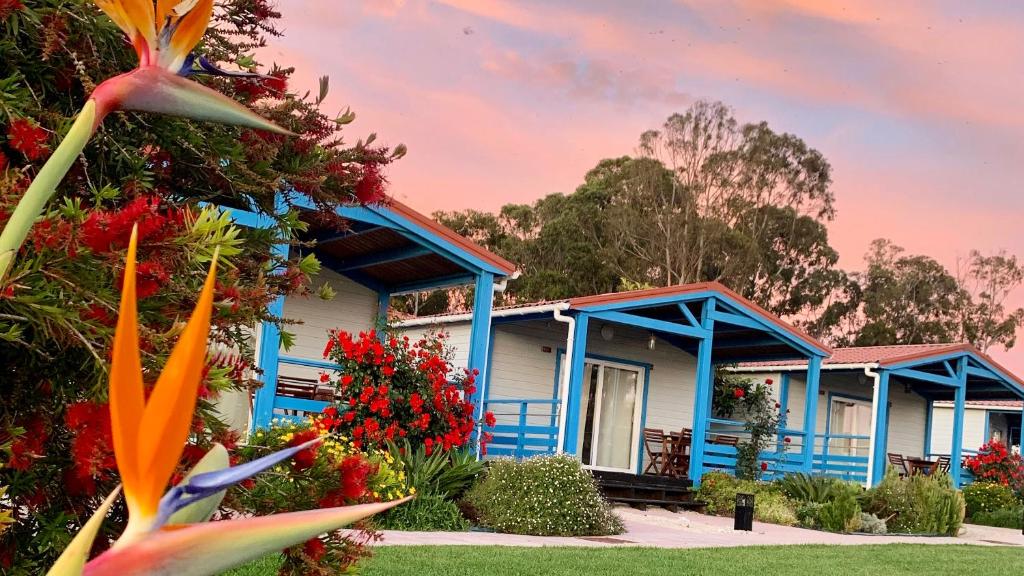 una casa azul con flores delante en Costa do Vizir Beach Village, en Porto Covo