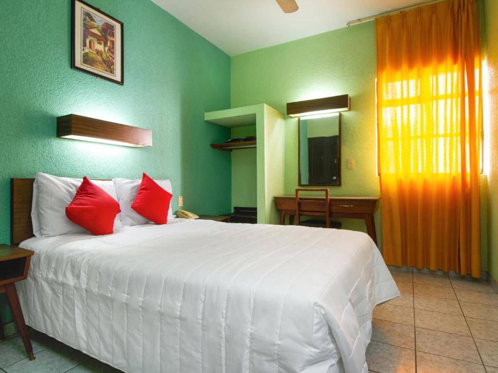 - une chambre avec un grand lit blanc et des oreillers rouges dans l'établissement Hotel Canada, à Guadalajara