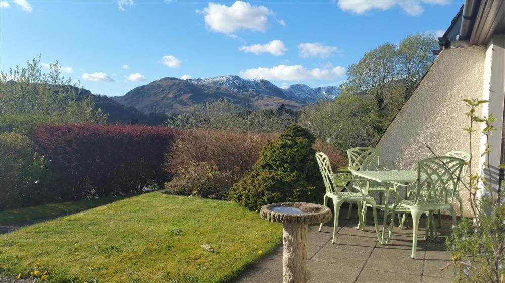 a table and chairs on a patio with mountains in the background at Rothay 18 in Ambleside