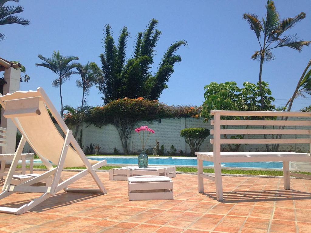 een paar bankjes naast een zwembad bij LAS PALMERAS HOSTAL in Barranca