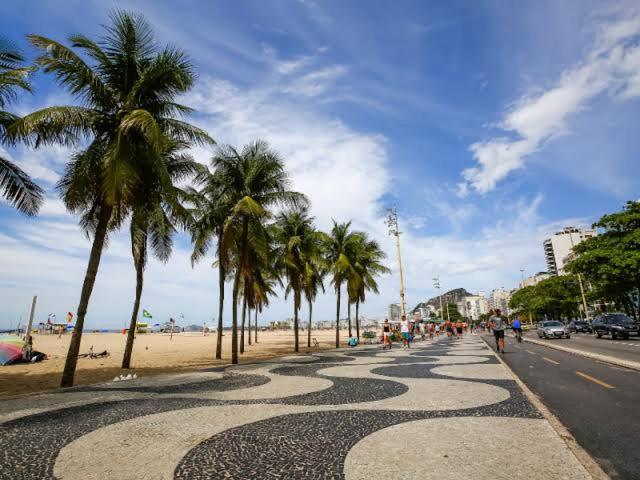 a sidewalk with palm trees on the beach at Ap grande e ultramoderno e no ponto estratégico de Copacabana in Rio de Janeiro