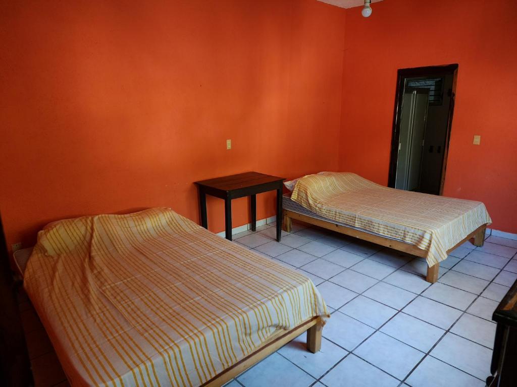 2 camas en una habitación con paredes de color naranja en CASA PLAYITA MELAQUE, en San Patricio Melaque