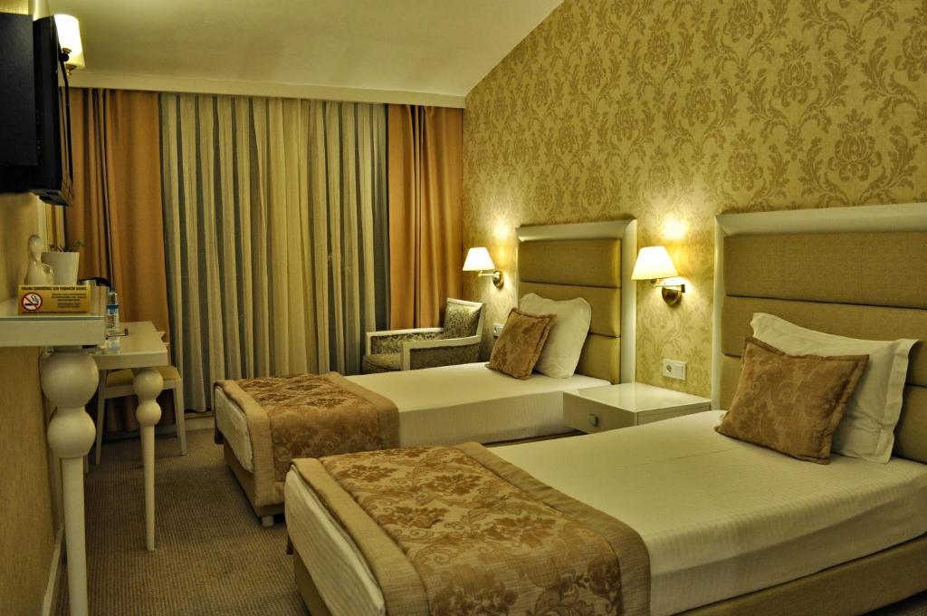 una habitación de hotel con 2 camas y una silla en Hotel Edirne Palace, en Edirne