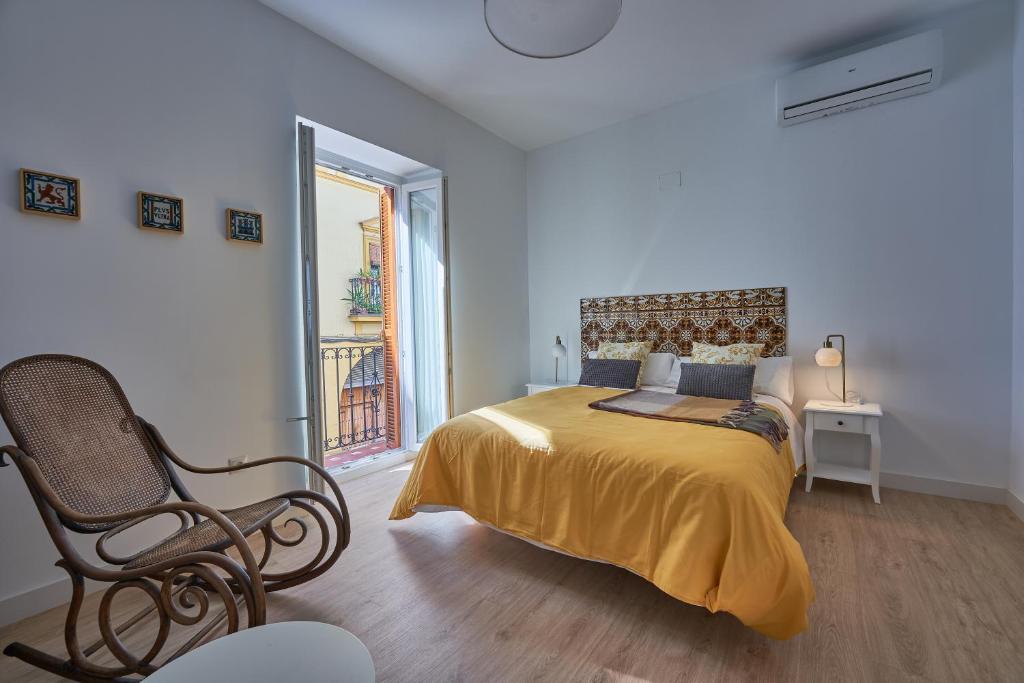 a bedroom with a bed with a chair and a window at Casa Pureza in Seville