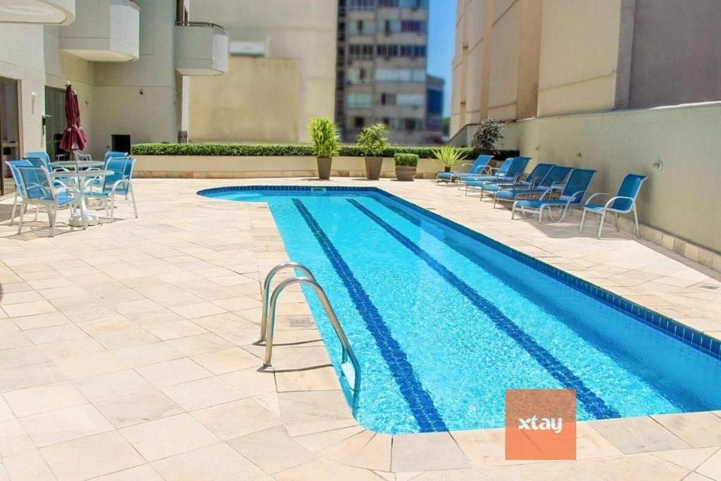 a swimming pool with chairs and a table and a building at Xtay Privillege Botafogo in Rio de Janeiro