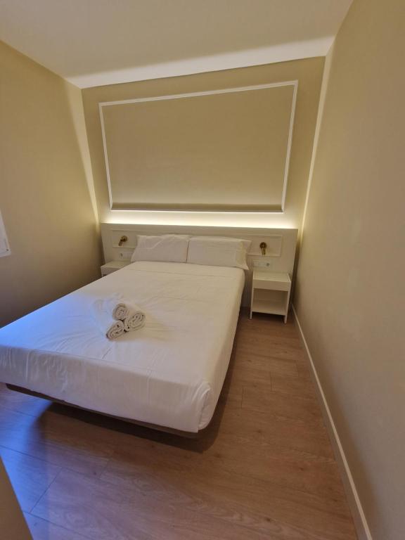 Habitación pequeña con cama con sábanas blancas. en Le Petit Palü- Barco, en Madrid