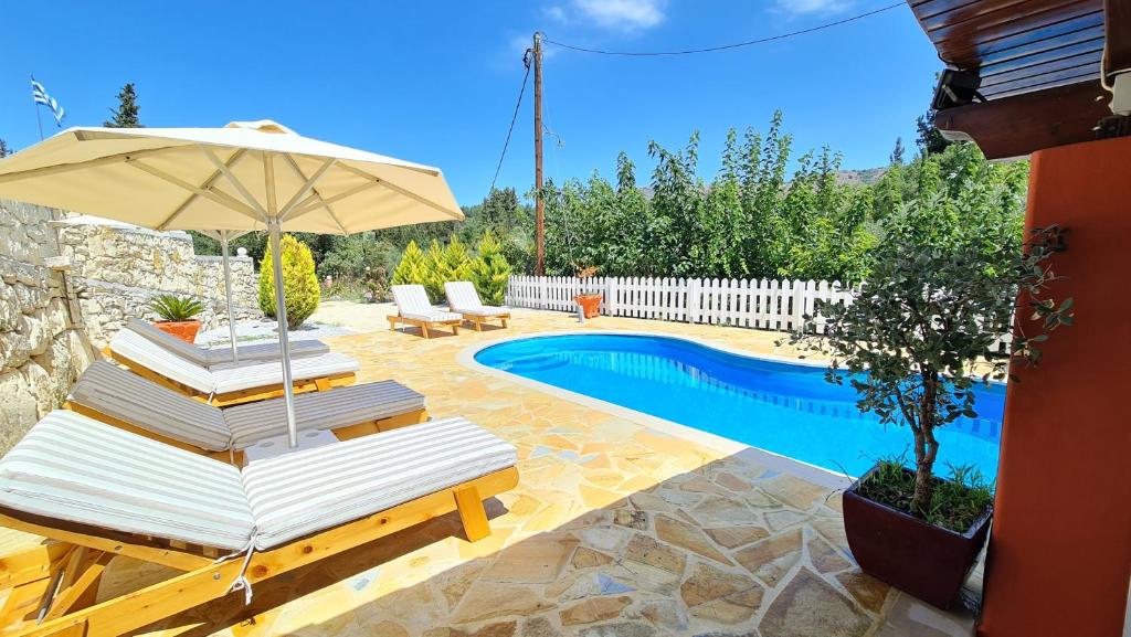 a patio with chairs and an umbrella and a pool at Villa Nikolas in Gavalochori