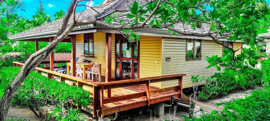 MOOREA - The Golden Reef Bungalow Nuku Hiva في Temae: منزل أصفر مع سطح خشبي كبير