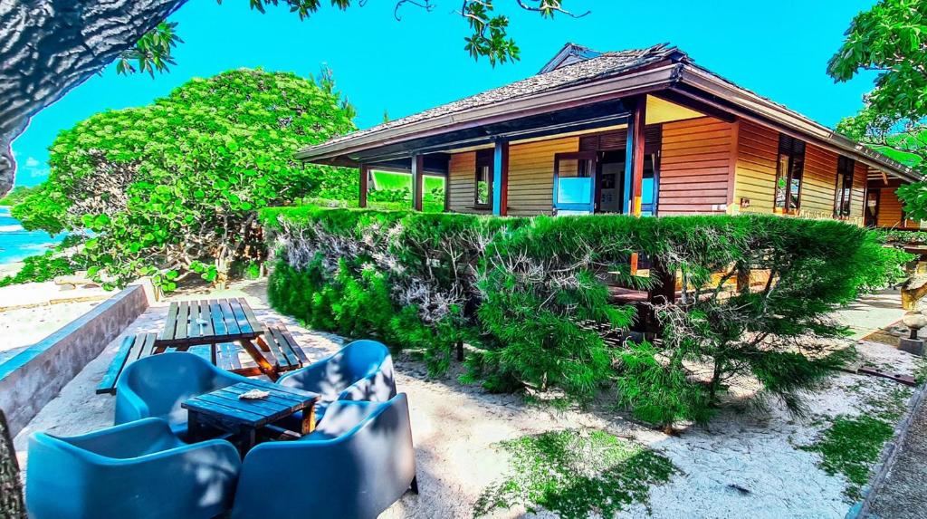 une maison sur la plage avec des chaises bleues devant elle dans l'établissement MOOREA - The Golden Reef Bungalow Bora Bora, à Temae