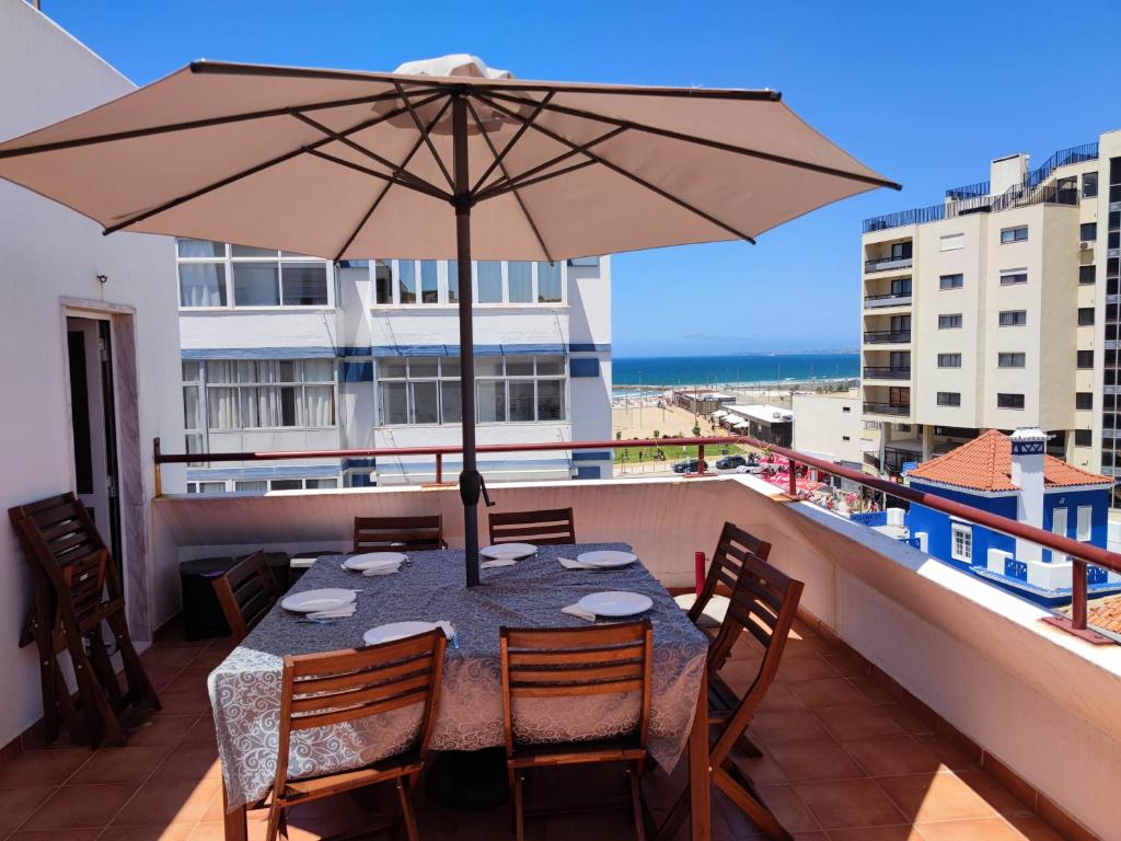 a table with an umbrella on a balcony at Amazing Terrace Costa da Caparica in Costa da Caparica