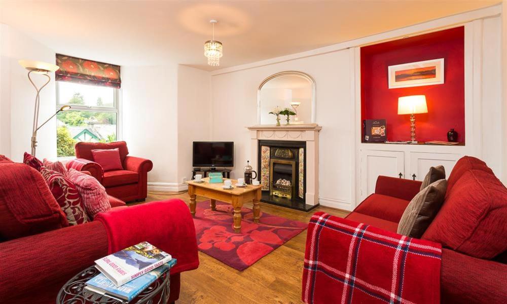 een woonkamer met rode meubels en een open haard bij Biskey Steps in Bowness-on-Windermere
