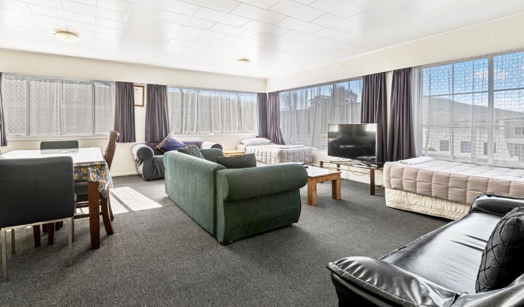 Kowhai Motel Rotorua في روتوروا: غرفة معيشة مع كنب وتلفزيون