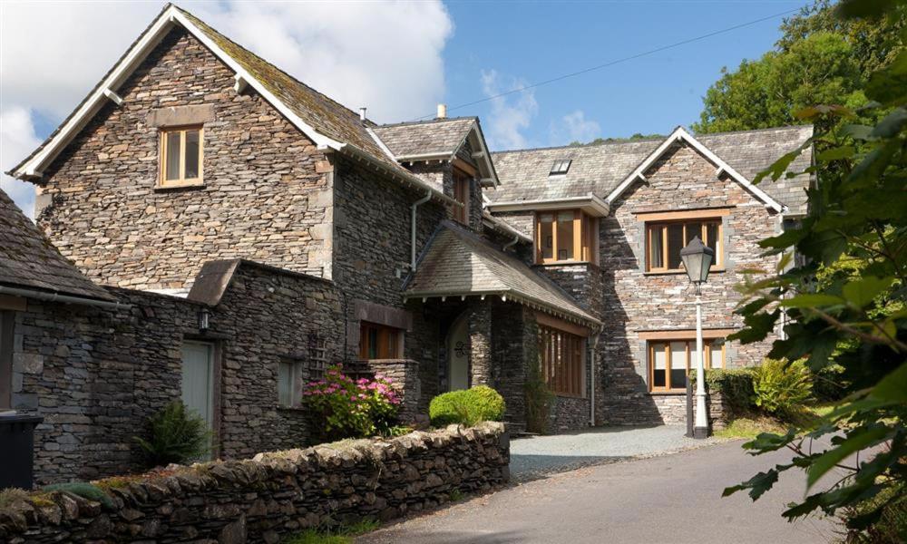 a large stone house with a stone wall at The Old Coach House in Troutbeck