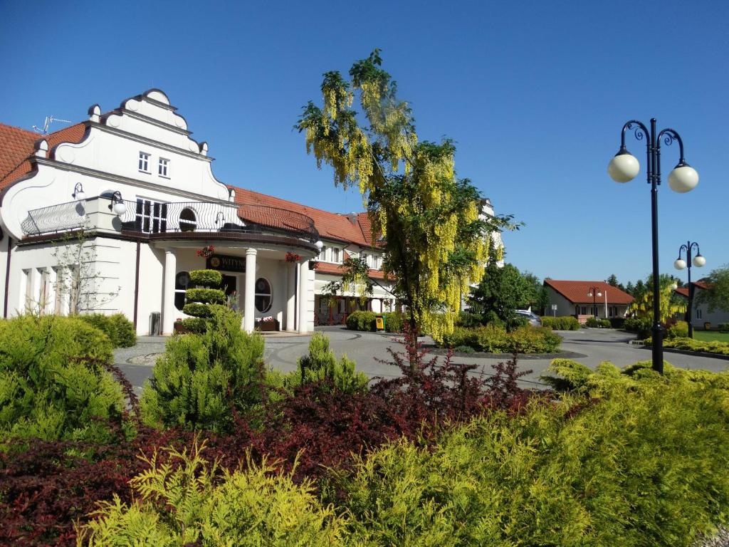 een wit huis met een rood dak bij Hotel Wityng in Ślesin